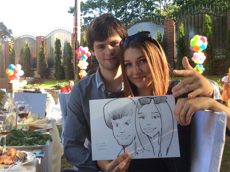 шаржист стоит на фоне выставки шаржей зал Кальварийская на свадьбе